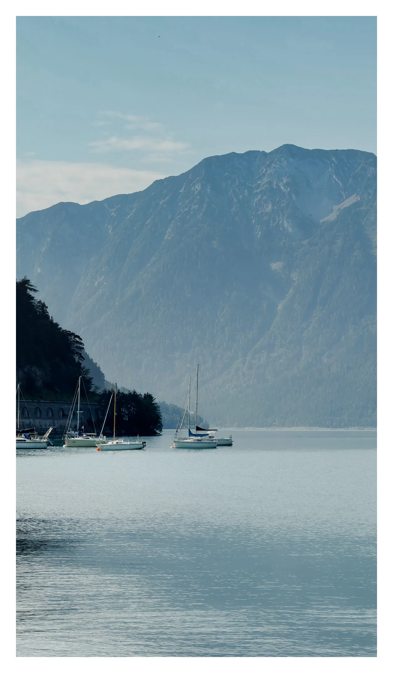 Zeilboten op de Achensee met een hoge bergwand op de achtergrond