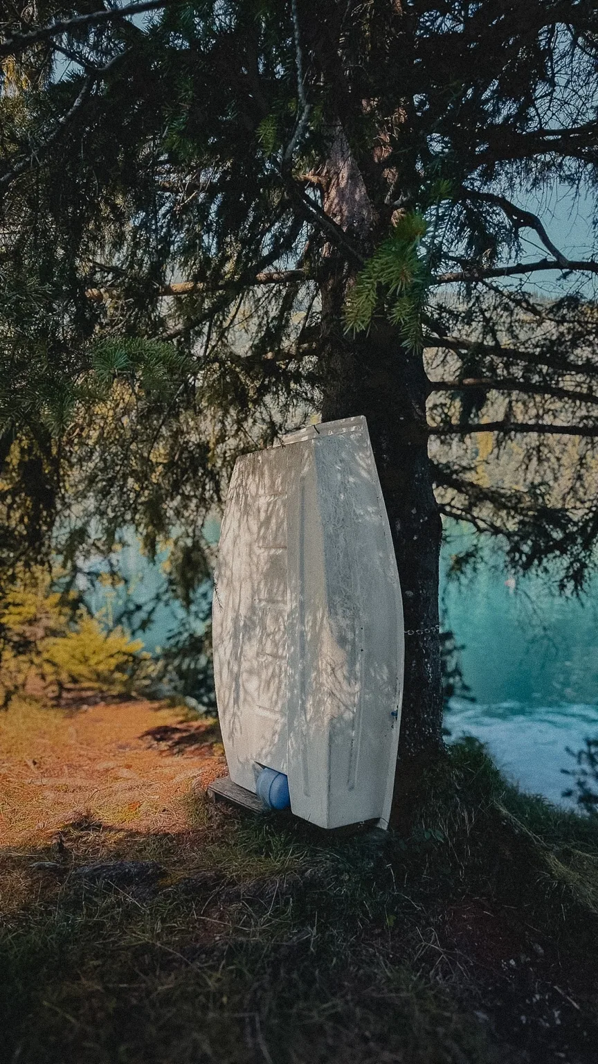 Een omgekeerde witte roeiboot tegen een boom aan de Achensee