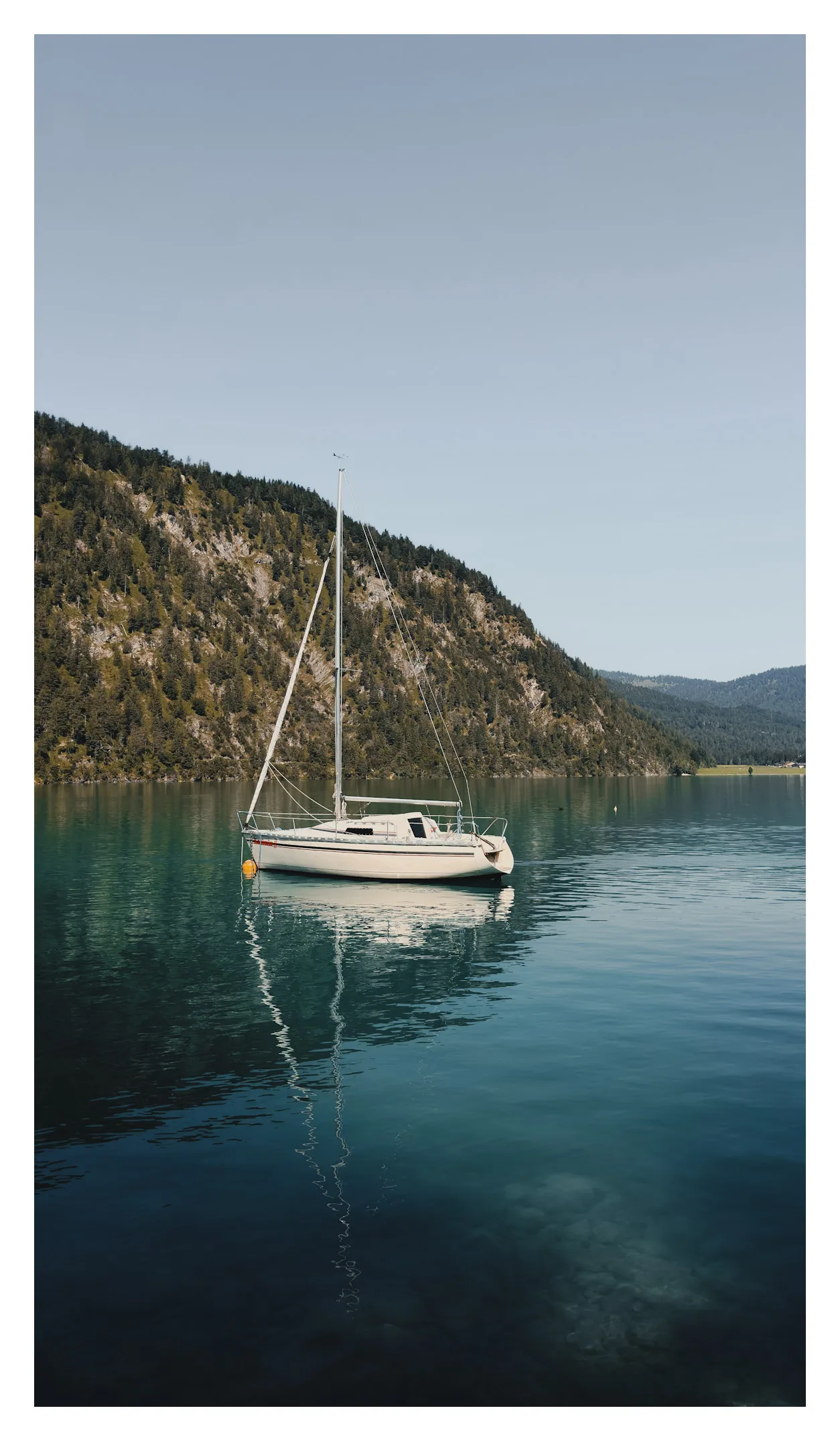 Een witte zeilboot op het rustige water van de Achensee